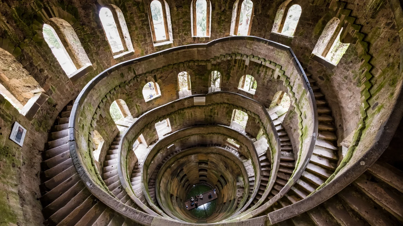 Interior view looking down into the deep circular brick shaft and arched windows of St. Patrick's Well in Orvieto