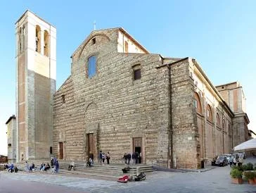 Wheelchair user going up the 5-metre ramp beside the front steps of the unfinished brick Montepulciano Cathedral