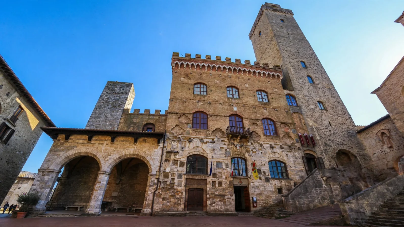 Palazzo Comunale of San Gimignano on Piazza del Duomo showing its stone facade, arched loggia, and entrance steps