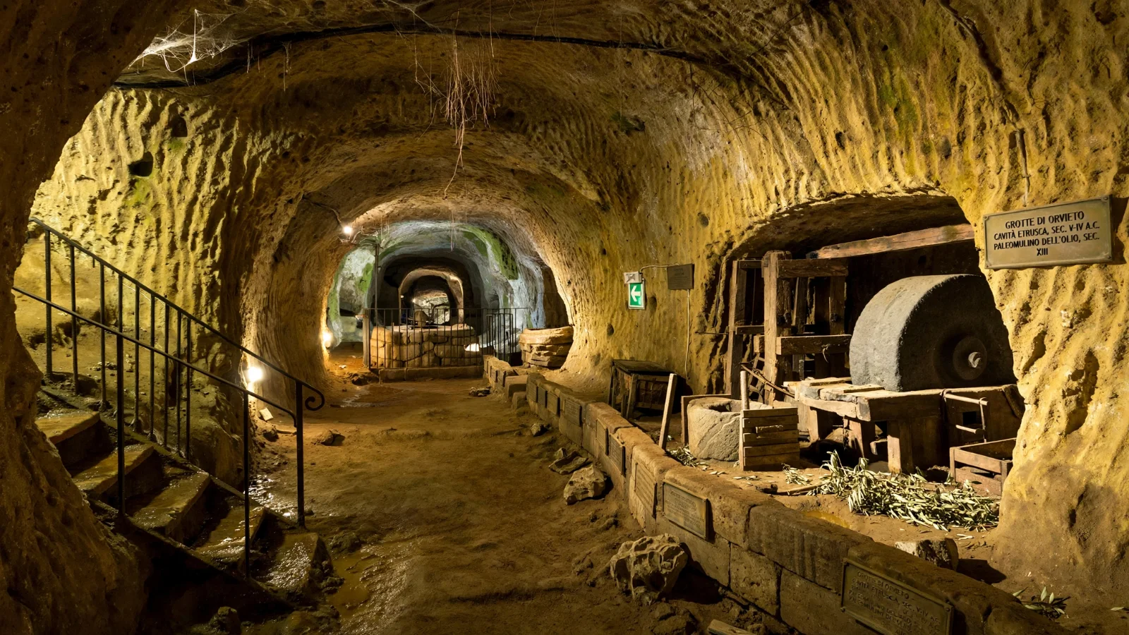 Ancient subterranean cave carved into yellow volcanic tuff rock in Orvieto with olive press stones and carved niches