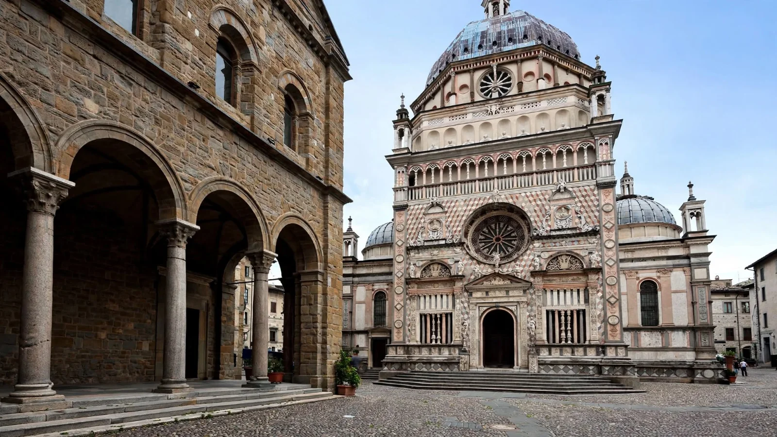 Piazza Duomo in Bergamo showing the marble facade of the Colleoni Chapel with steps in front, alongside the lion porch of the Basilica of Santa Maria Maggiore
